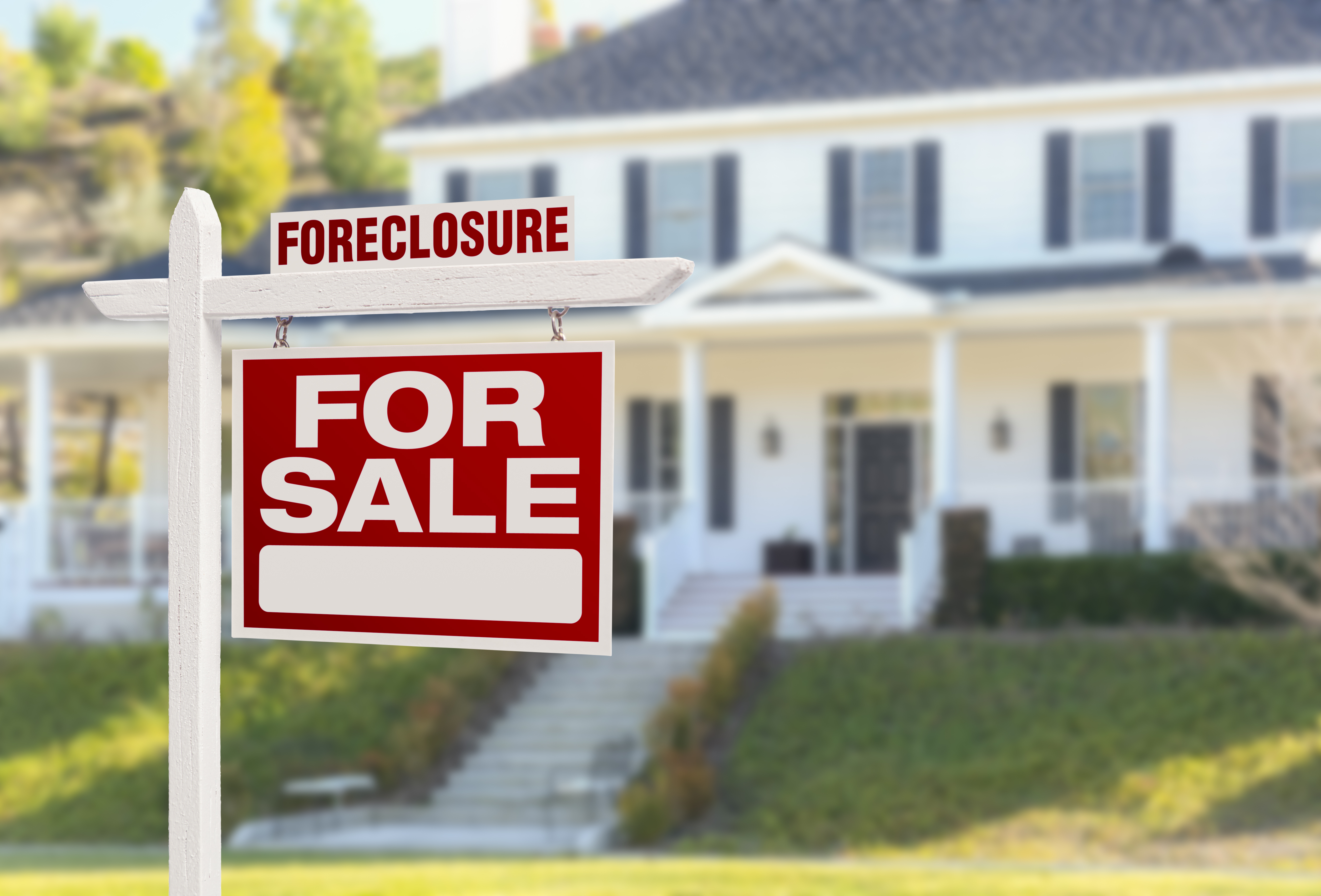 a home with a foreclosure fore sale sign in the front yard
