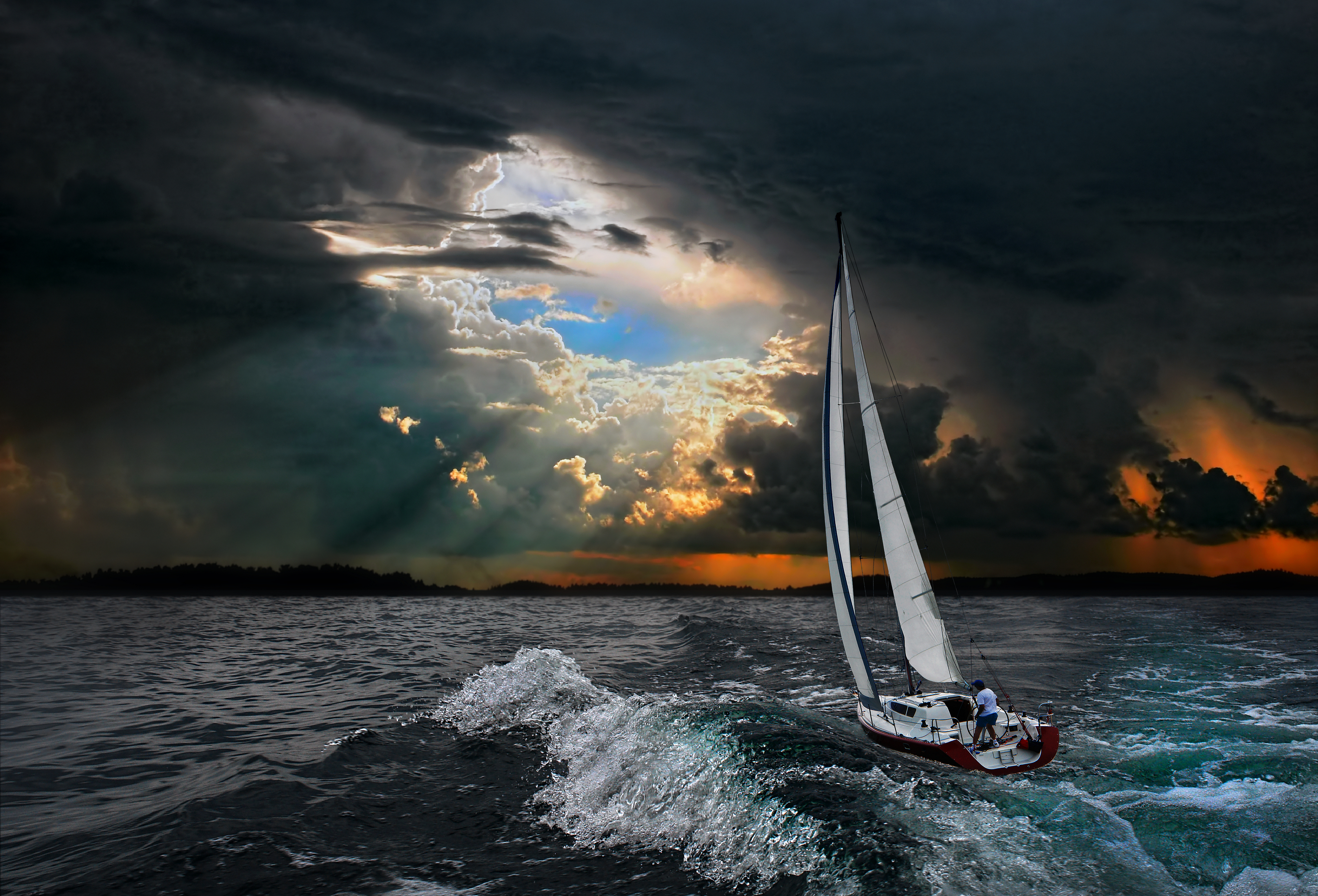 Sailboat on stormy sea with sunlight in the distance