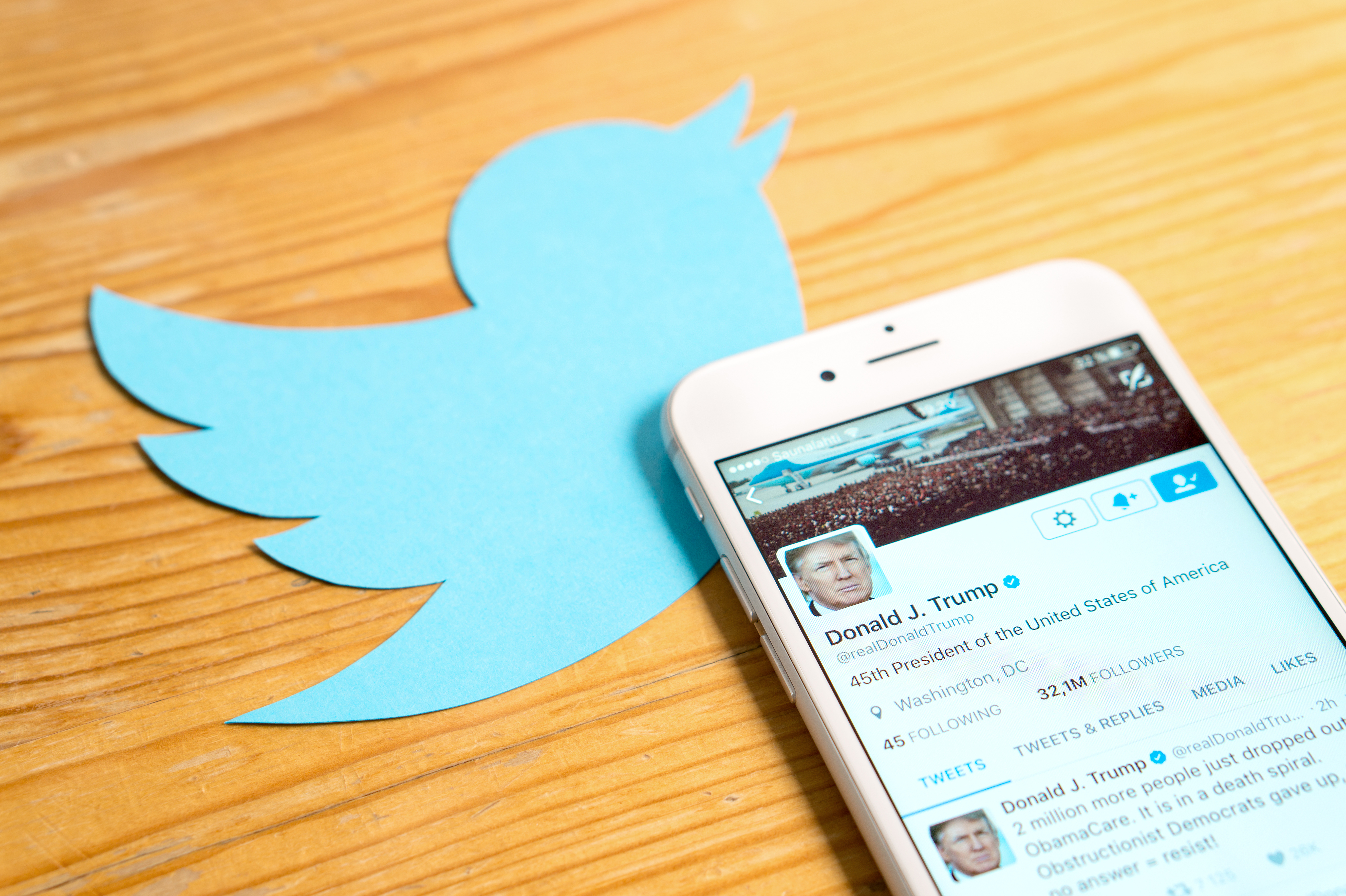 Phone with Donald Trump's Twitter account atop a cut out Twitter logo